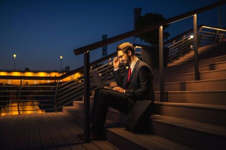 Handsome elegant businessman working on a computer outdoors in the city.の写真素材