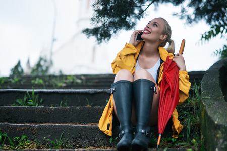 Cute girl sitting on a stairs and talking on a mobile phone.の写真素材
