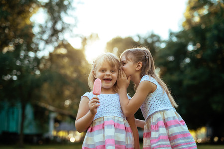 Two sisters having fun outdoors and eating an ice cream.の写真素材