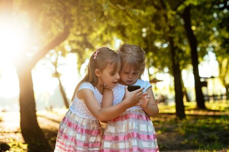 Two cute sisters playing with mobile phone together.の写真素材