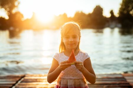Cute young girl eating watermelon outdoors.の写真素材