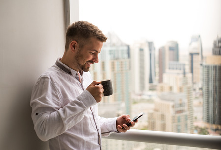 Young businessman enjoying coffee break while texting.の写真素材