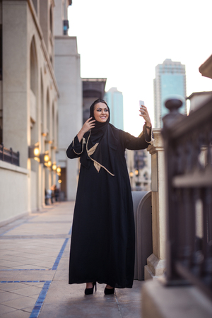Beautiful muslim girl making a selfie with her phone.の写真素材