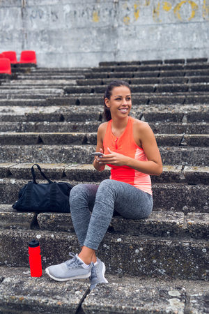 Young sporty girl texting on a mobile phone while training.の写真素材