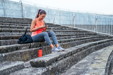 Young sporty girl texting on a mobile phone while training.の写真素材