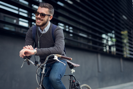 Handsome hipster enjoying city ride by bicycle.の写真素材