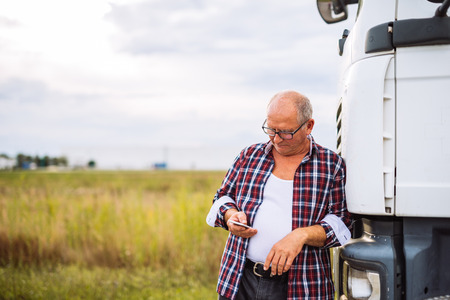 Senior truck driver checking his mobile phone.の写真素材