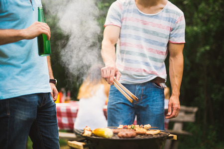 Friends making a barbecue on a picnic outdoors.の写真素材