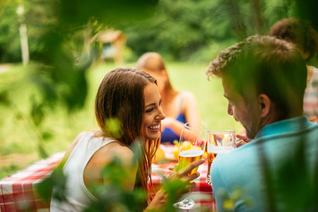 Couple toasting with beer on a picnic.の写真素材