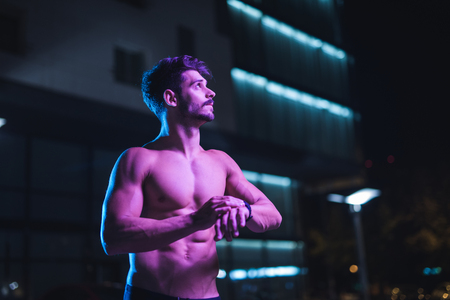 Portrait of a handsome shirtless man checking time on the watch.の写真素材
