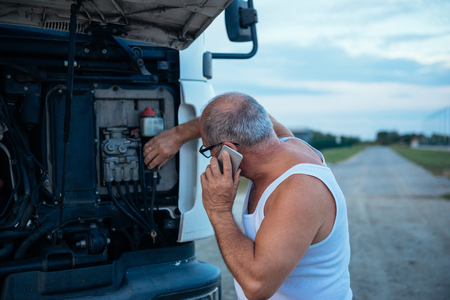 Driver calling for help and fixing a truck.の写真素材