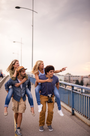 Friends piggybacking and enjoying sightseeing in the city.の写真素材