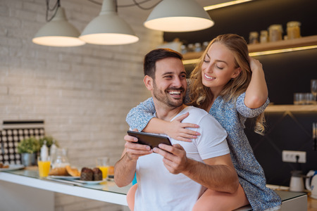 Couple using a digital tablet while having breakfast at home.の写真素材