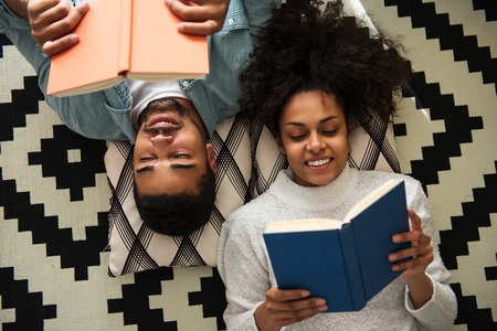 African american couple lying on the floor and reading books.の写真素材