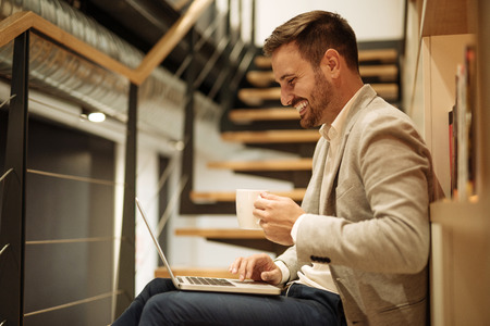 Handsome man working on a computer and drinking coffee.の写真素材