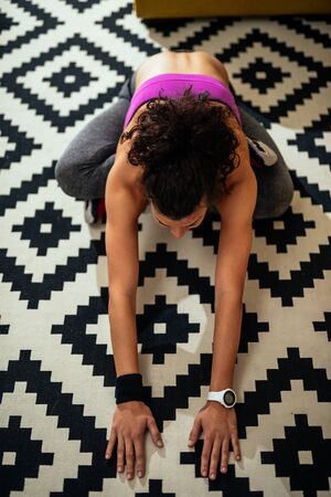 Beautiful girl stretching her muscles while doing fitness at home.の写真素材