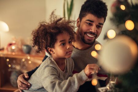 Cute girl decorating Christmas tree with a dad.の写真素材