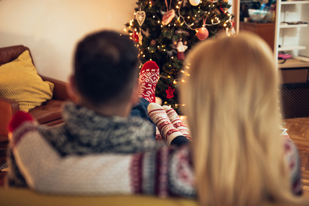Rear view of a couple cuddling while sitting on a sofa.の写真素材