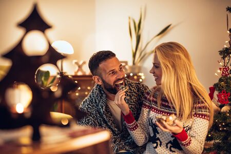 Happy couple enjoying tasty cookies at home.の写真素材