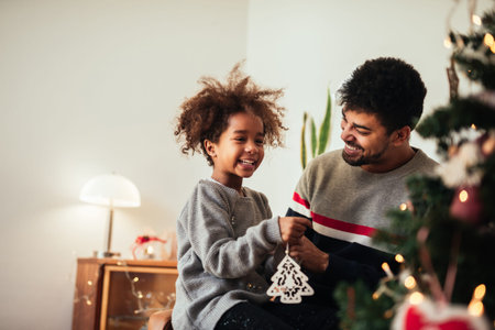 Dad and daughter decorating Christmas tree together.の写真素材