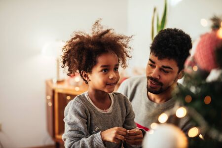 Cute african american girl decorating a Christmas tree at home.の写真素材