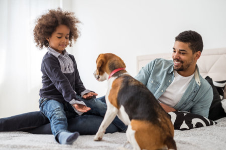 Cute little girl playing with her dog in the bed.の写真素材