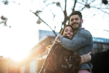 Beautiful couple sharing a warm hug on a sunny spring day.の写真素材