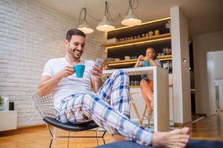 Handsome man drinking coffee and surfing the net in the morning at home.の写真素材