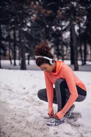 Portrait of a young woman training in the winter in the woods and listening to the music.の写真素材