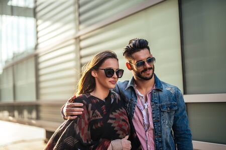 Close up portrait of an urban attractive couple wearing sunglasses walking down the street.の写真素材