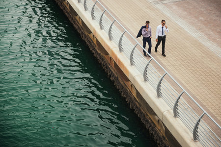Portrait from above of two businessmen having an outdoor meeting while walking by the river.の写真素材