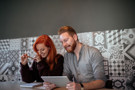 Photo of a cheerful couple working from home on a tablet.の写真素材