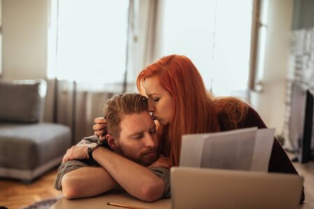 Shot of even minded couple working at home on laptop.の写真素材