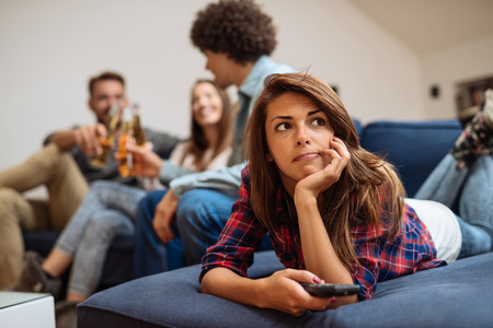 Group of friends having a good time in the apartment. Focus  on the girl who holds a remote controller.の写真素材