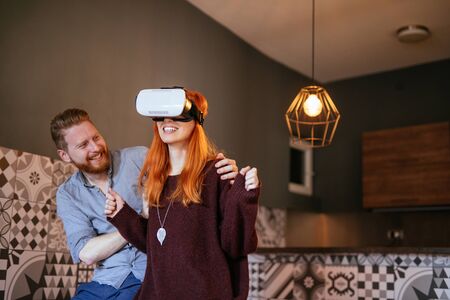 Photo of amazed couple using virtual reality headset at home.の写真素材
