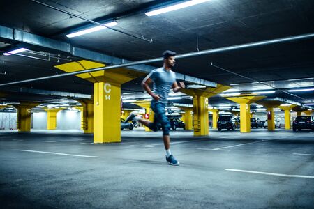 Blurred motion of an african american sportsman running on an underground parking.の写真素材