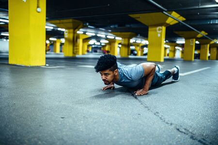 Handsome man doing push ups in an underground parking.の写真素材