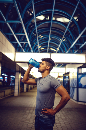 Handsome man stopping for a water while exercising.の写真素材