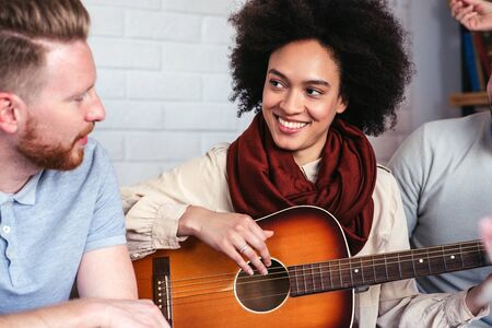 Group of friends playing a guitar and enjoying time together.の写真素材