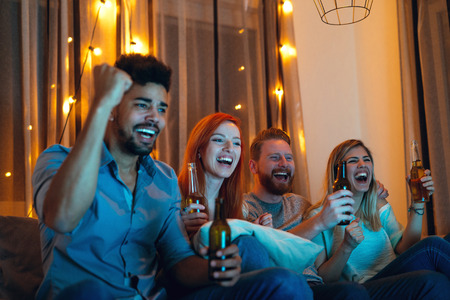 Shot of happy and satisfied friends enjoying watching a game at home.の写真素材