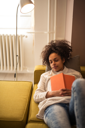 African american girl falling asleep with a book in her hands.の写真素材