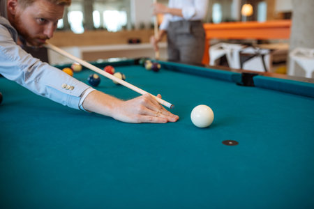 Handsome ginger man playing billiard in the office.