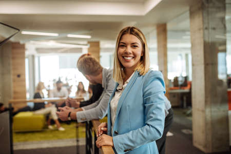 Portrait of a smiling young business woman surrounded by colleagues in the office.の写真素材