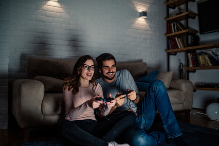 Photo of young couple playing video games at home at night.の写真素材