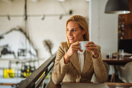 Portrait of young successful business woman enjoying drinking coffee in the cafe.の写真素材
