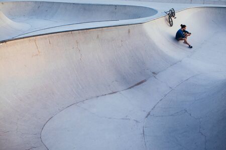 Young BMX driver making a break and checking his phone.の写真素材