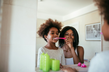 Photo of african american mother and daughter brushing teeth in the morning.の写真素材