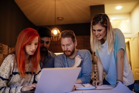 Photo of four business people working on the new project at home while using laptop.
