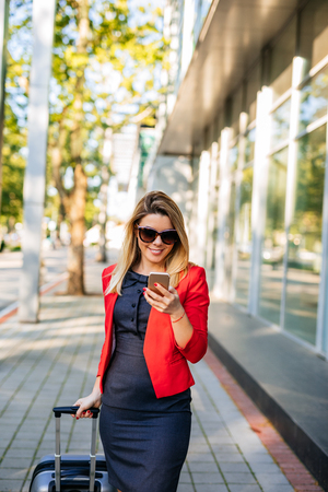 Beautiful woman texting on the phone and getting ready for business trip.の写真素材