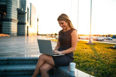 Beautiful woman working outdoors while having a coffee.の写真素材